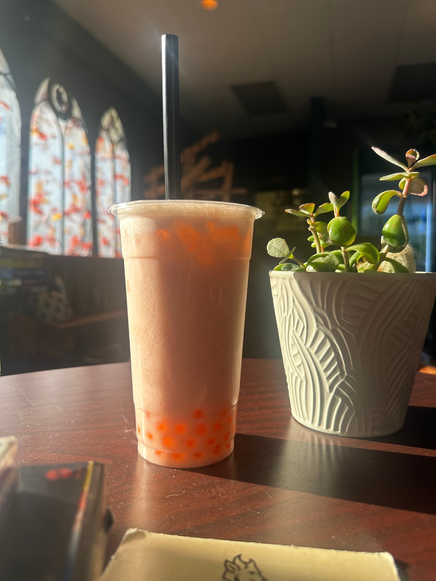 Strawberry milk tea in afternoon sun by the café's arched windows